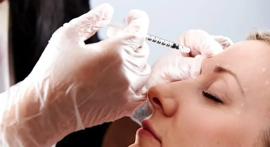 A woman receiving a botox shot in her forehead.