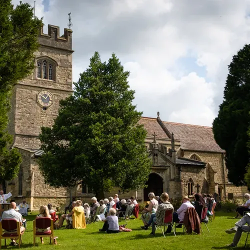 People sit on picnic chairs in the St Laurence churchyard
