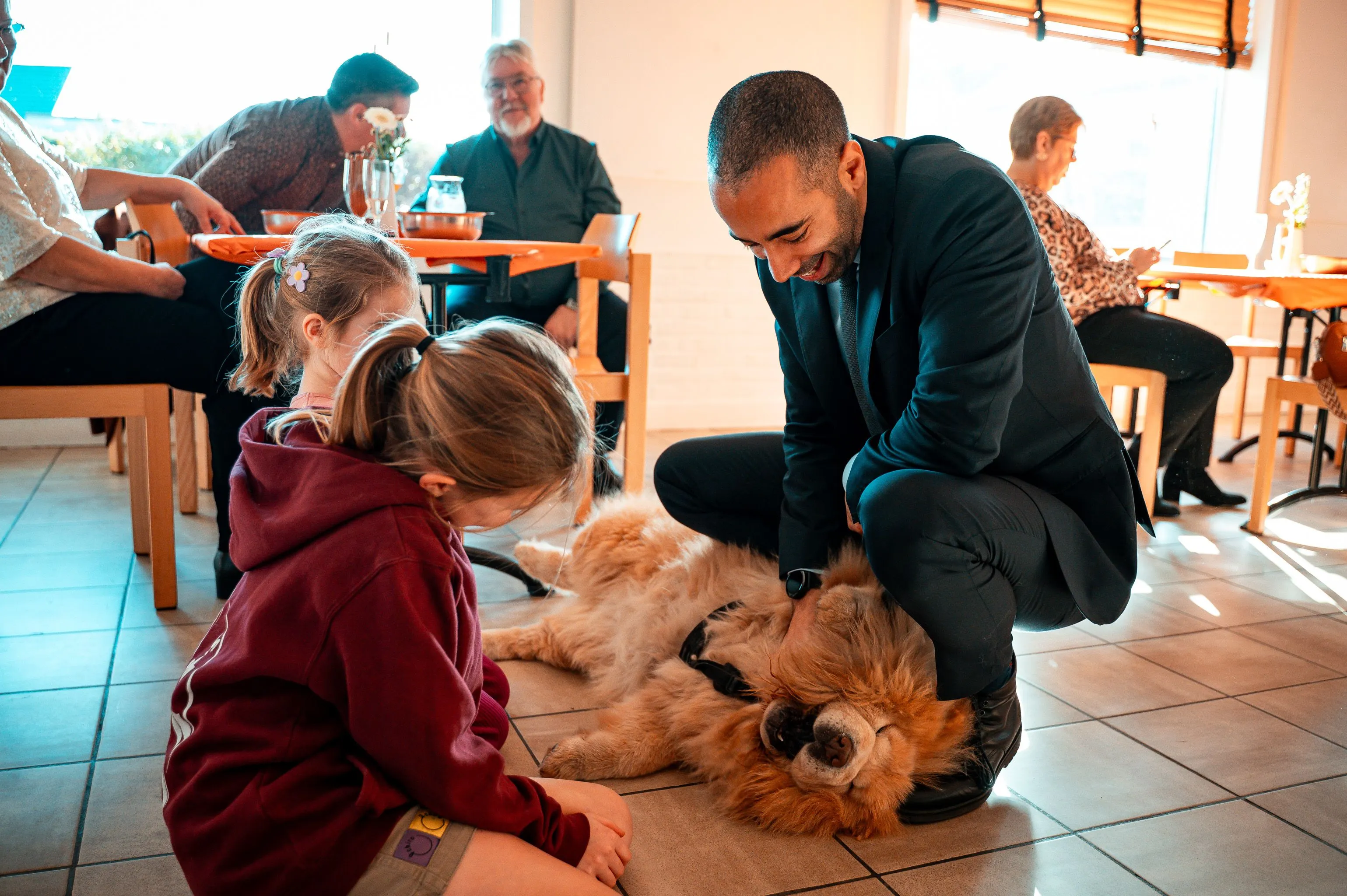Calm therapy dog interacting with children and older adults during a therapy visit, demonstrating the friendly temperament needed for therapy dog training in Northwest Arkansas.