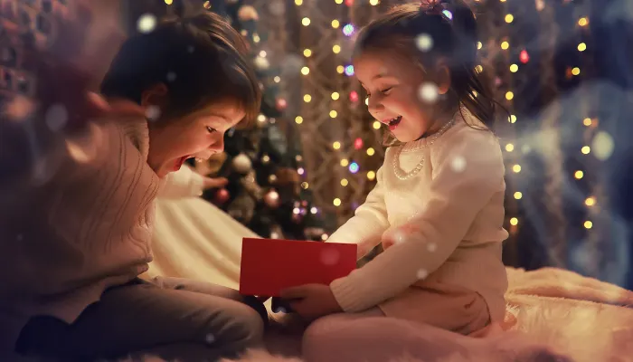 Two kids opening a christmas present and being so happy.