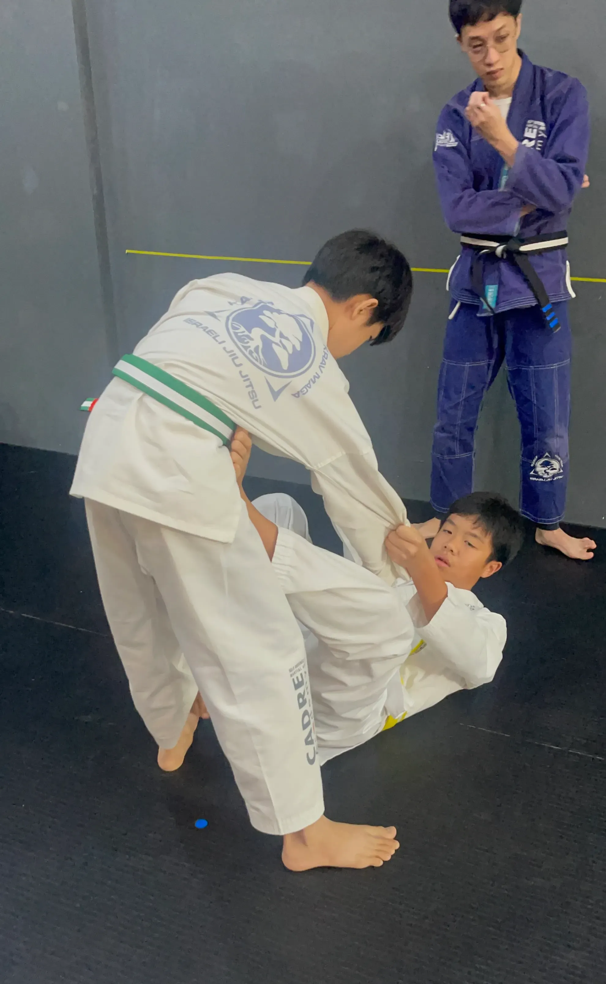 Kids practising Integrated Jiujitsu with instructor supervision at CADRE Academy