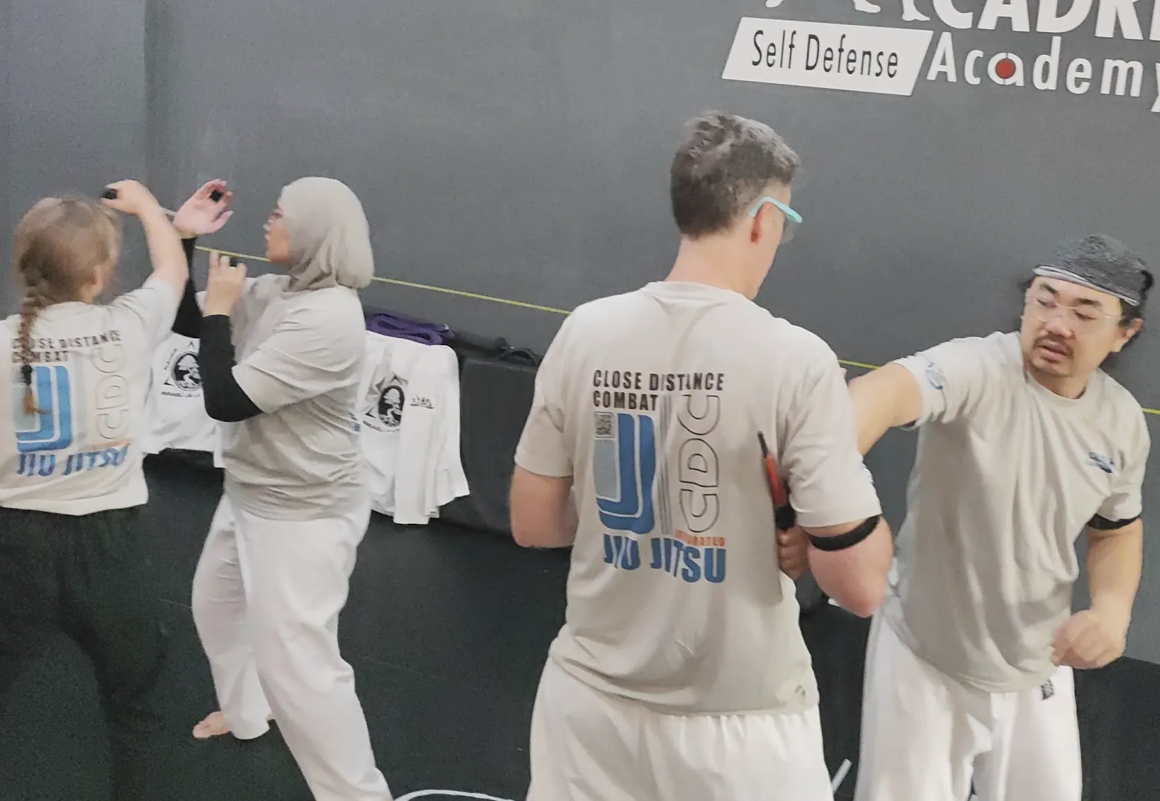 Adults practising standing self-defence and partner interaction during Integrated Jiujitsu training at CADRE Academy in Singapore.