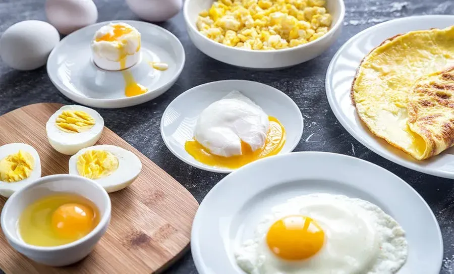 an image of a breakfast table with various egg dishes such as scrambled eggs, hard boiled eggs, and an omelette