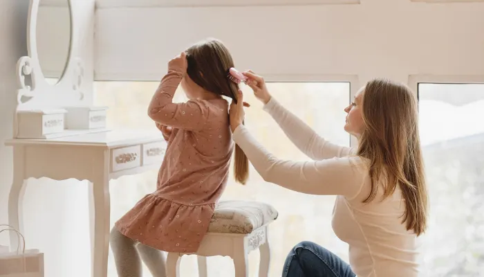 A mom doing her daughter's hair.