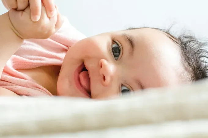 A baby lying on their back in a crib, looking alert and awake