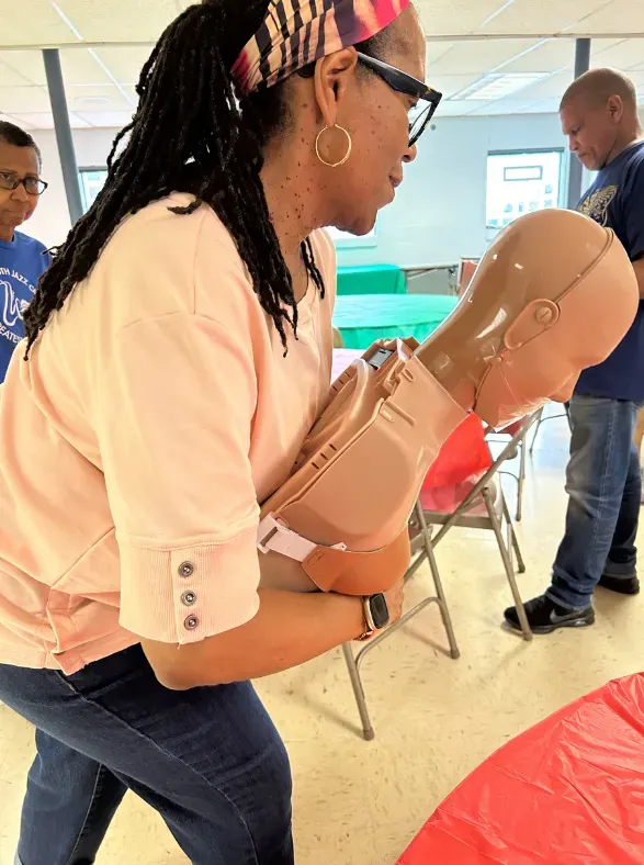 Member of New St. John Baptist Church doing choking relief on manikin