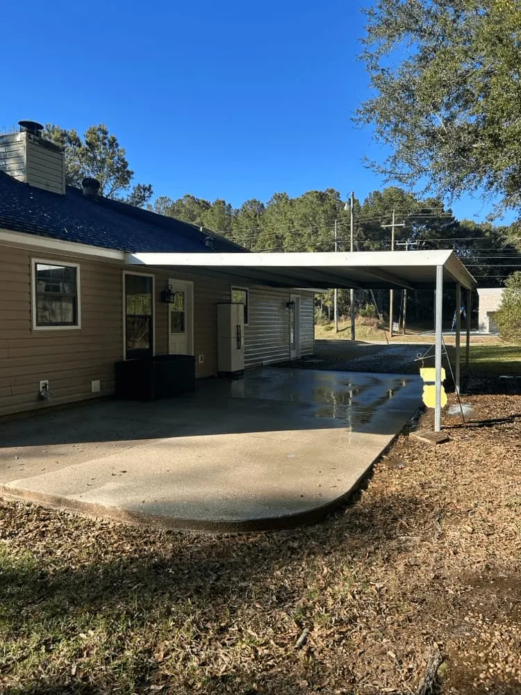 <alt=“After exterior house cleaning in Mobile County Alabama showing clean siding and restored concrete patio and driveway.”>
