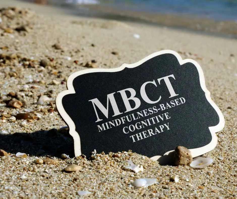 A sign in the sand with MBCT on it 
