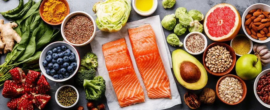 A bright colorful picture of healthy foods like salmon, berries, nut and seeds, fruits, veggies, whole grains.