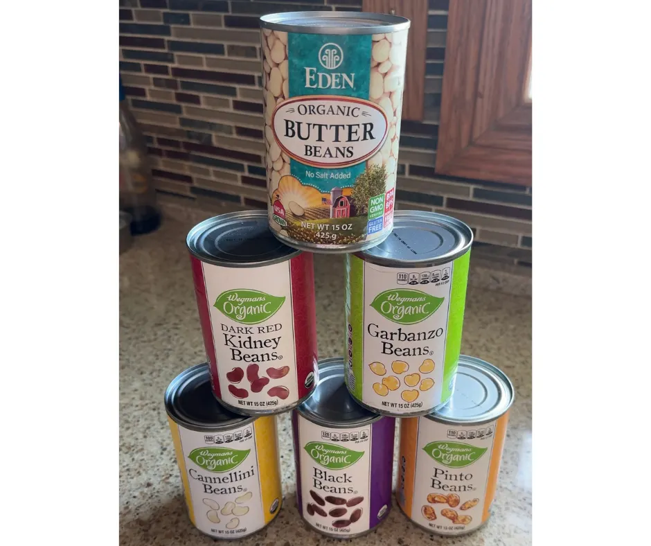 Stacked cans of beans including chickpeas, black beans, and white beans for everyday plant-based meals