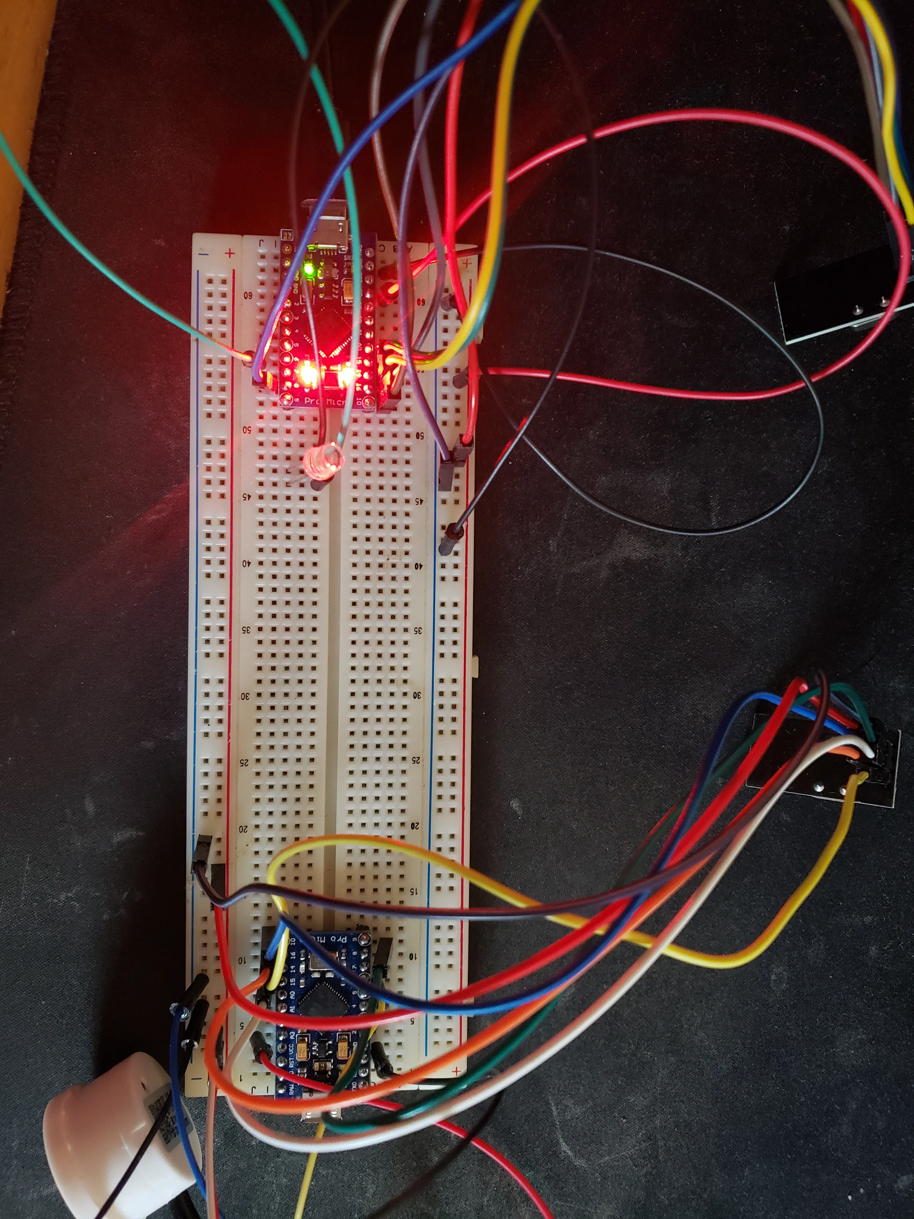2 separate Arduino micros on a single breadboard with each connected to a NRF24L01 module. One micro is wired to the non contact fluid sensor, the other wired to an LED