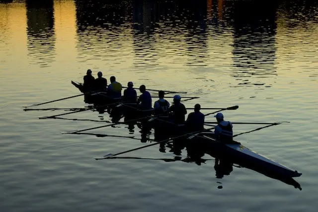 Team rowing smoothly in alignment to the rising dawn on the horizon