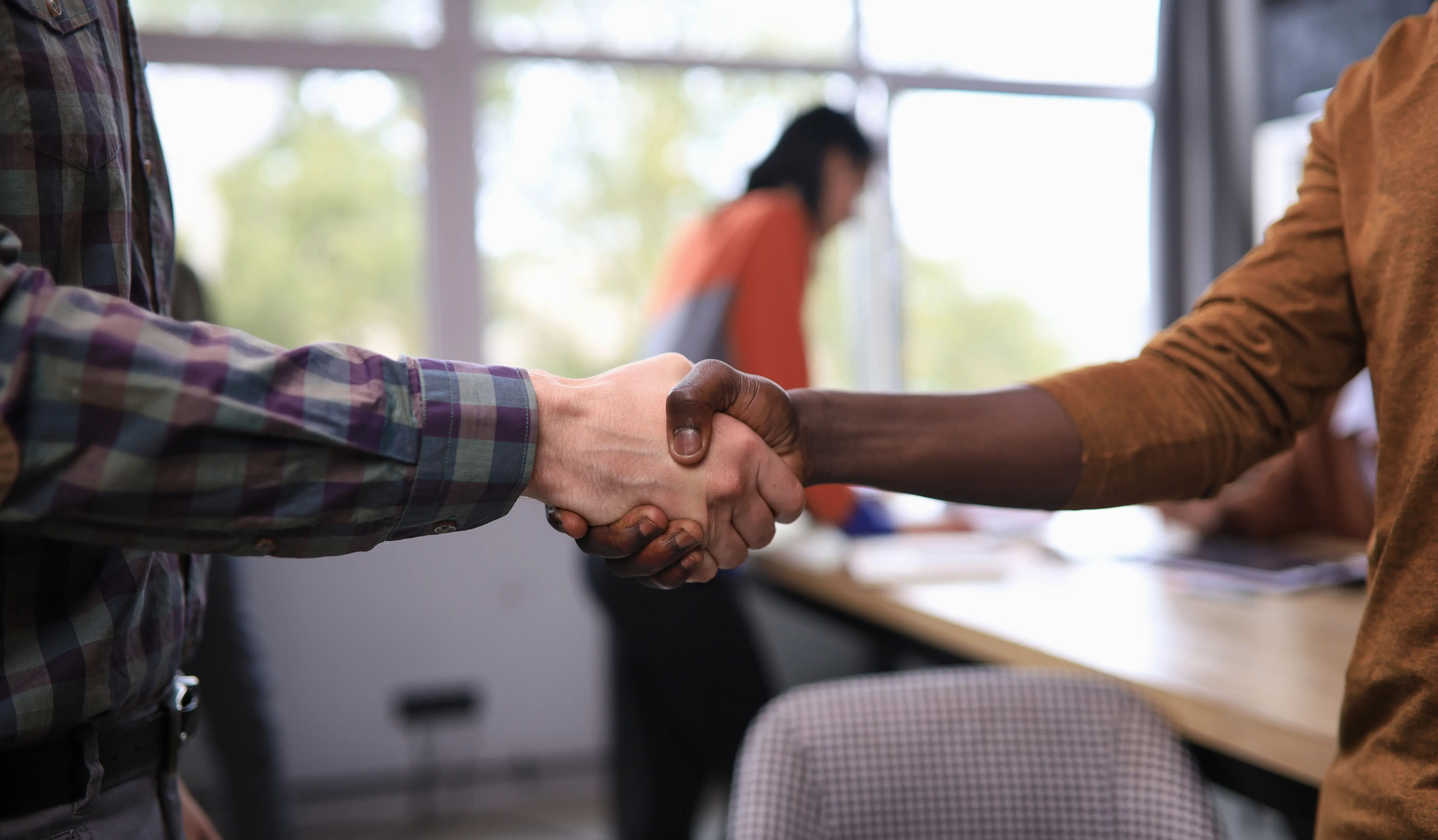 Close-up of a handshake symbolizing a successful land sale agreement.