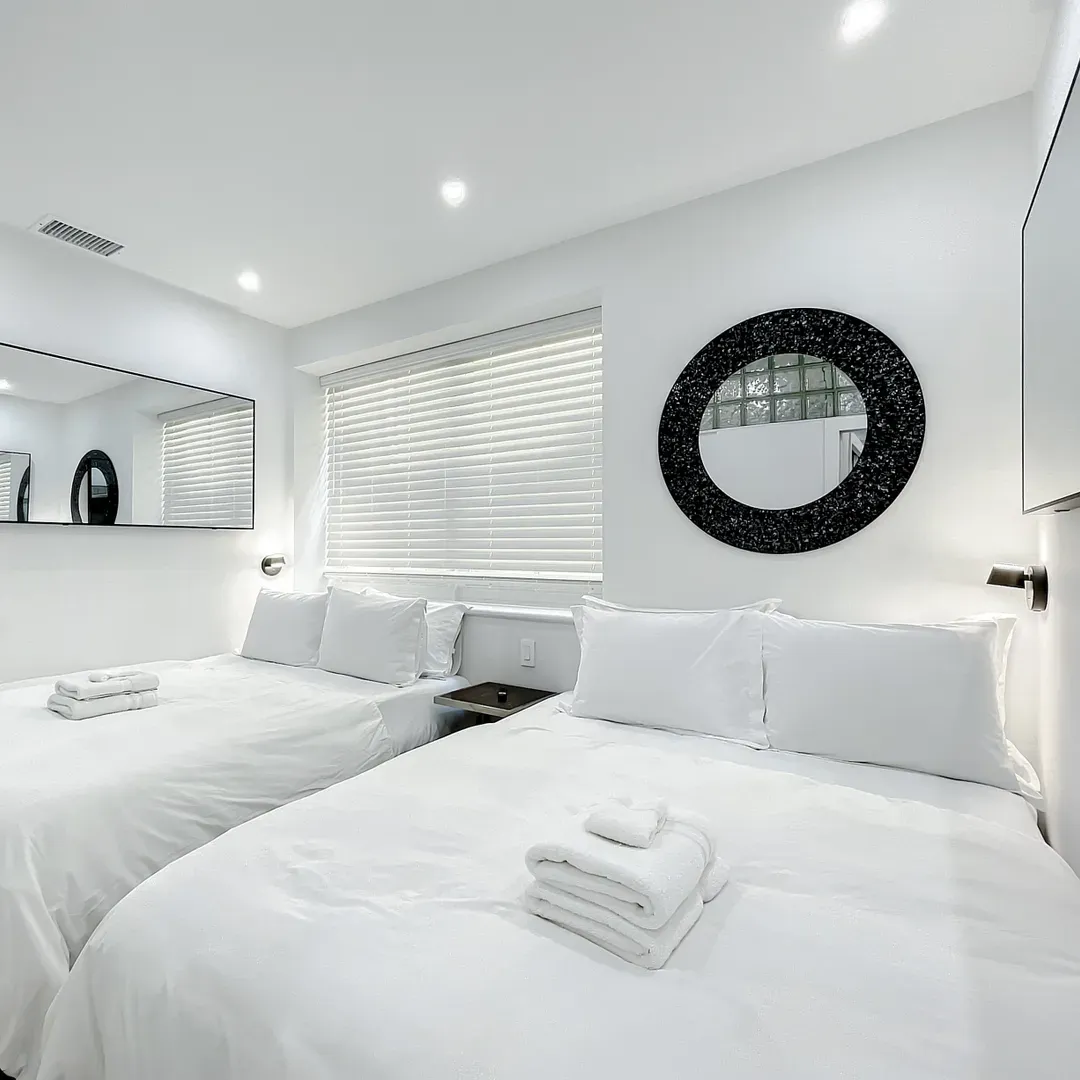Our rental home's second bedroom comfortably accommodates two guests with its setup of two plush queen beds dressed in soft linens for deep relaxation.