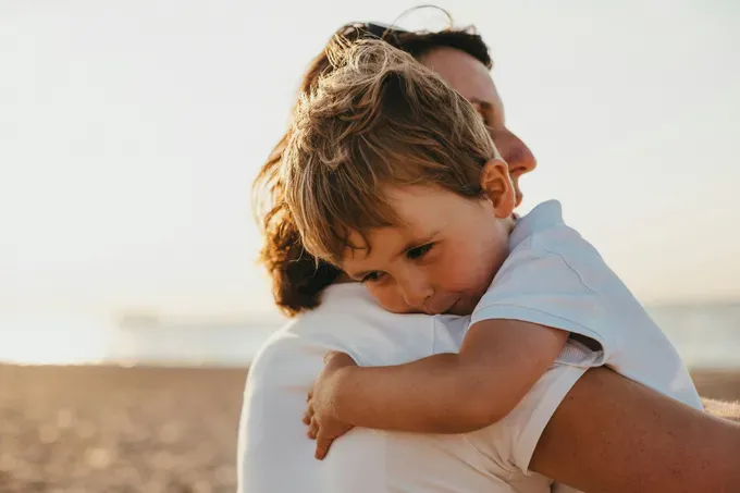 mom embracing her little child while spending time in the beach