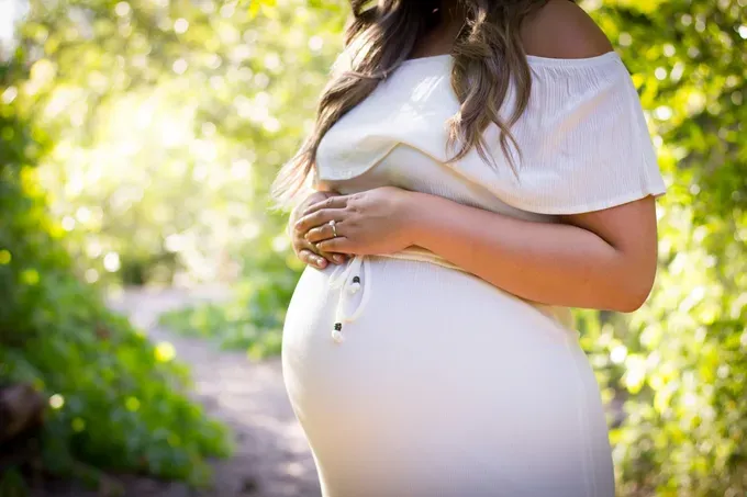 Expecting mother resting hands on her belly.