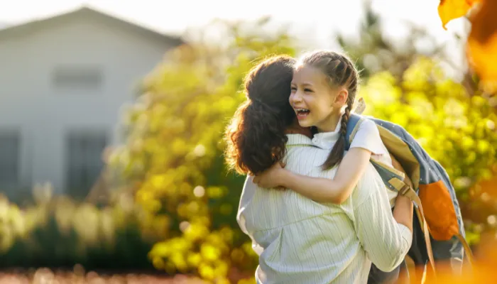 A mom and her daughter hugging after school.