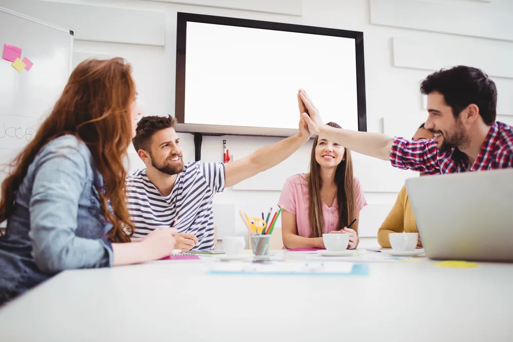 collegues giving high five in meeting