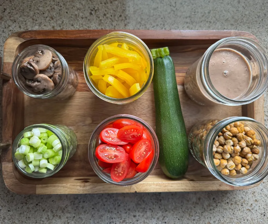 Prepared salad ingredients in jars for a zucchini ribbon garden salad with sautéed mushrooms and chickpea croutons