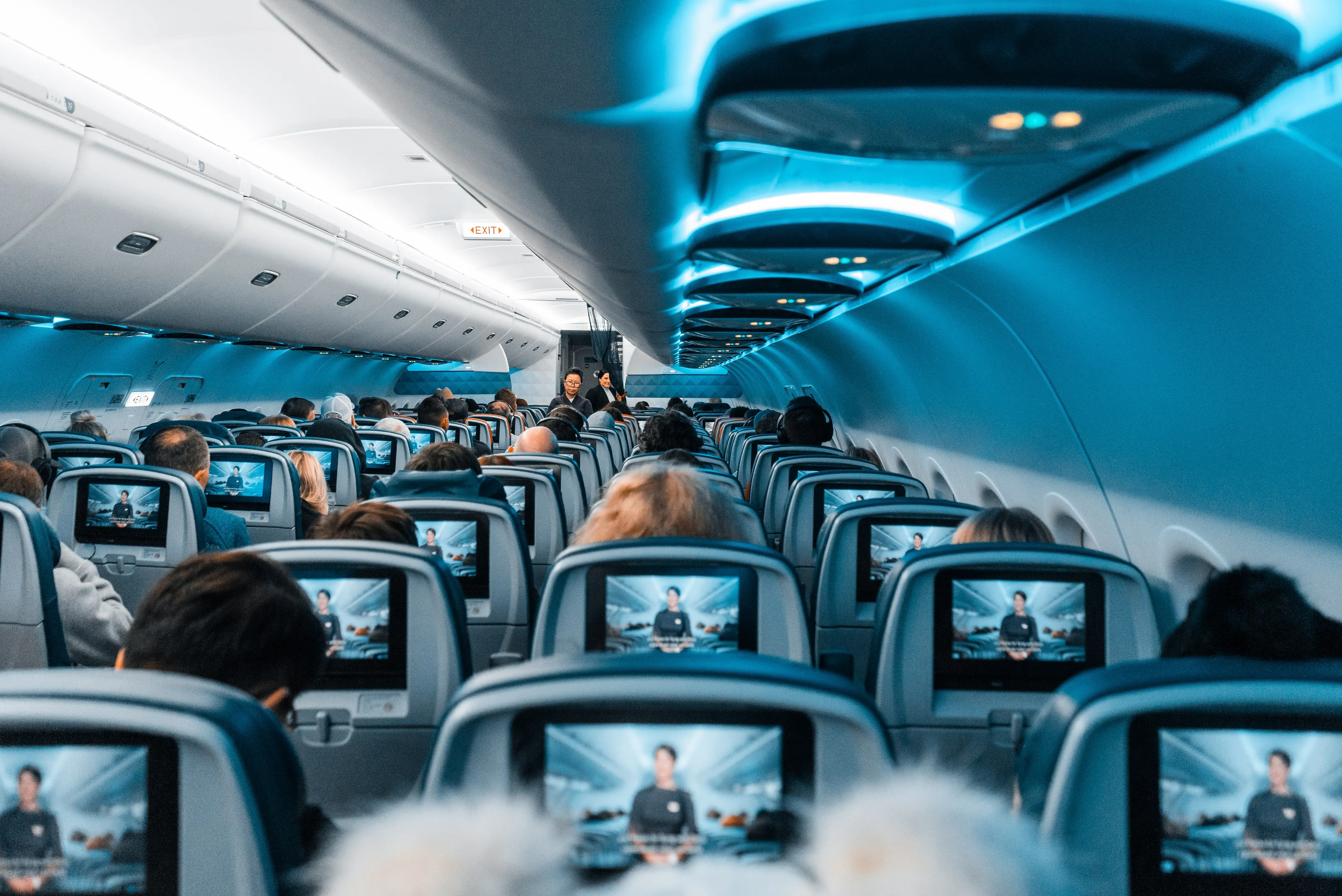 people seated on plan enjoying in-flight entertainment