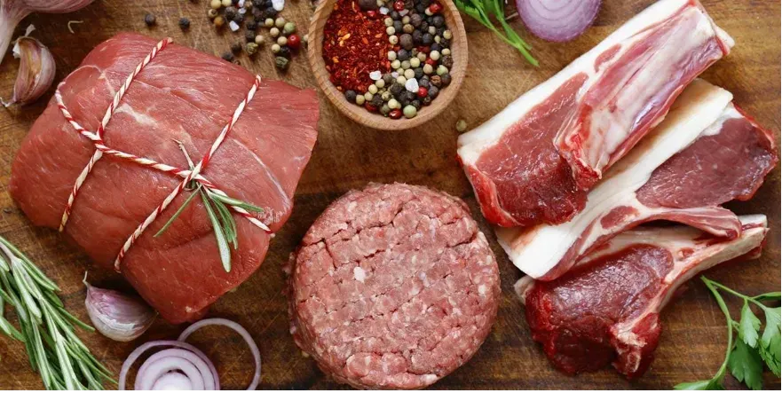 A Butchers table with various types of meat and meat cuts.