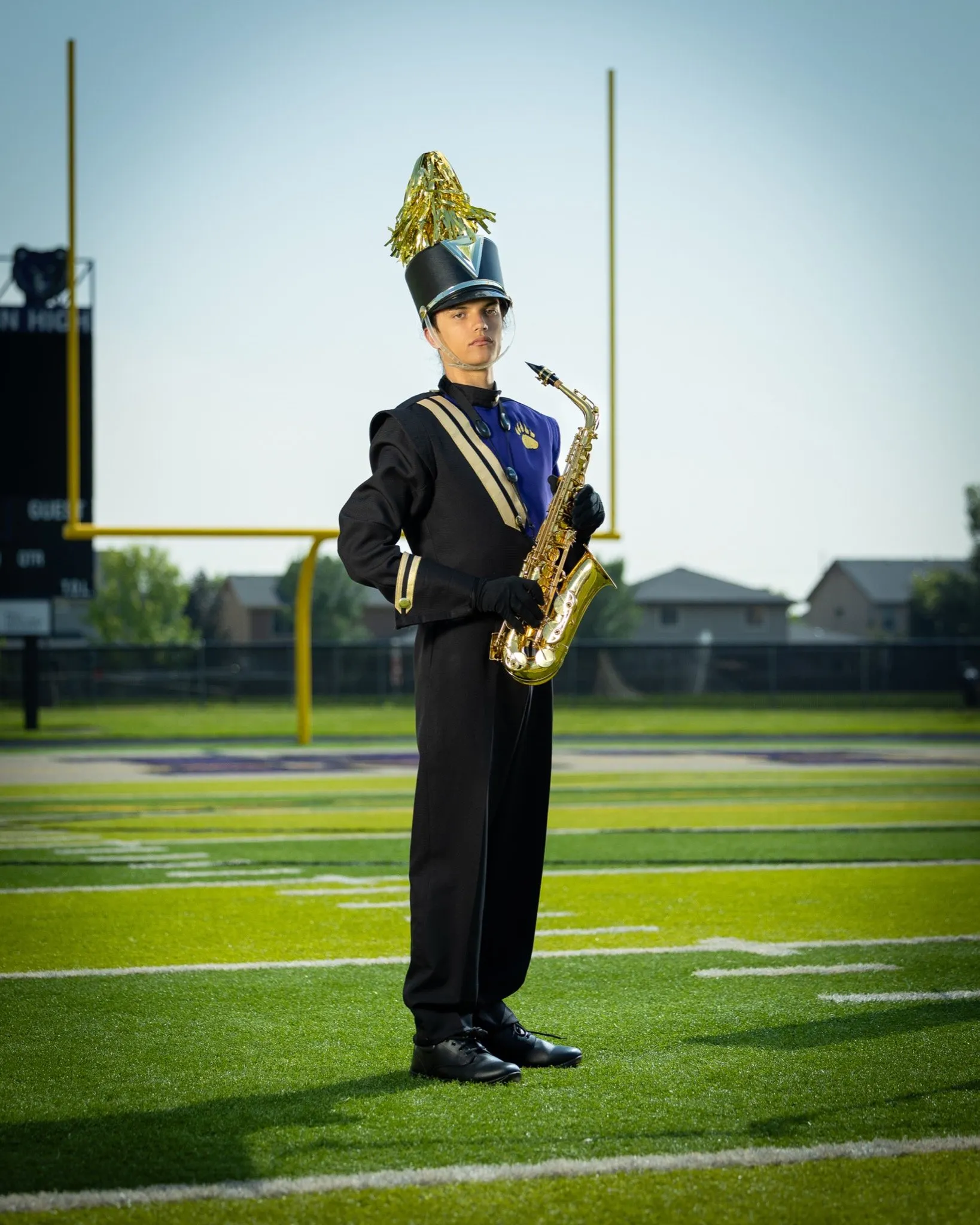 [marching band, saxophone, uniform] Band member in full dress uniform with alto saxophone on football field