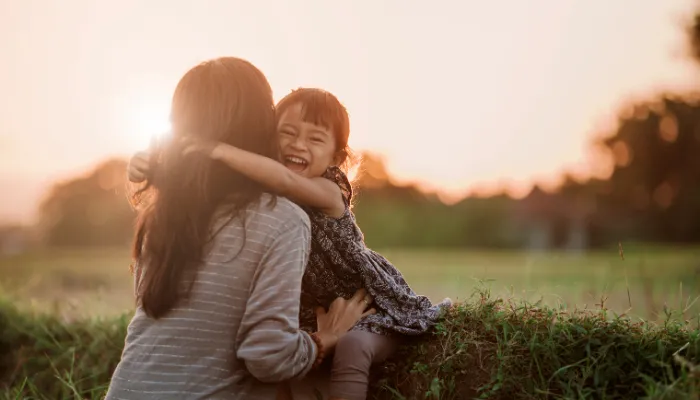 A mom hugging her child outdoors.