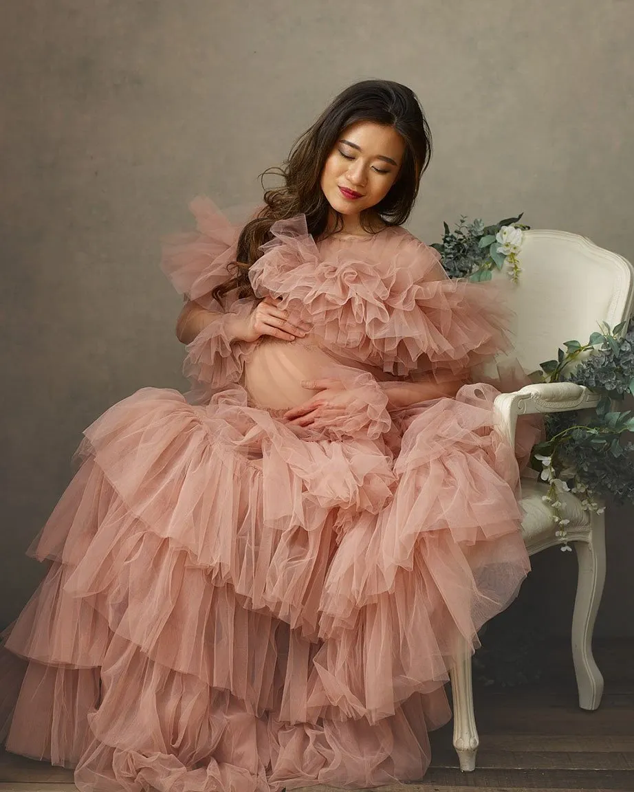 Maternity portrait of woman wearing a light pink tulle dress sitting on a chair covered in flowers