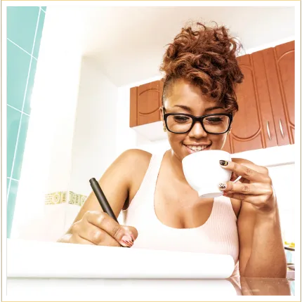 Young woman with tea cup smiling and writing on a notebook