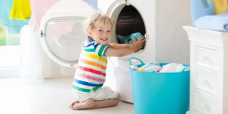 Small toddler boy doing laundry and happy.