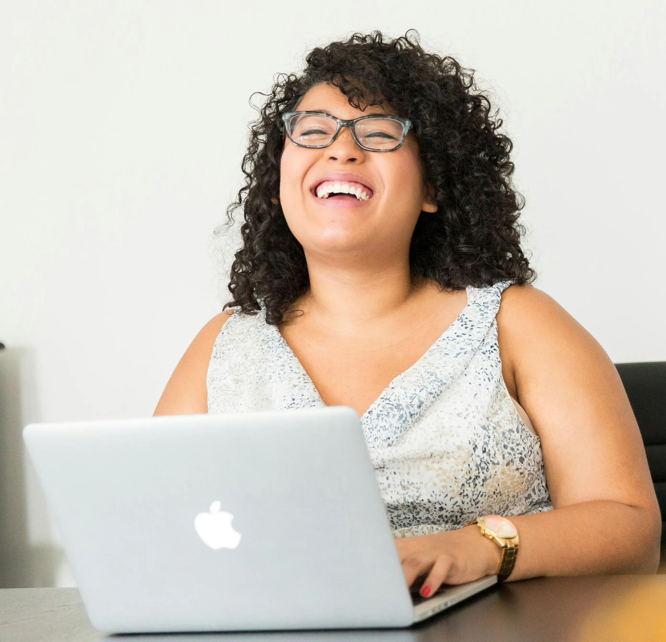 mujer sonriendo en frente de una computadora portatil