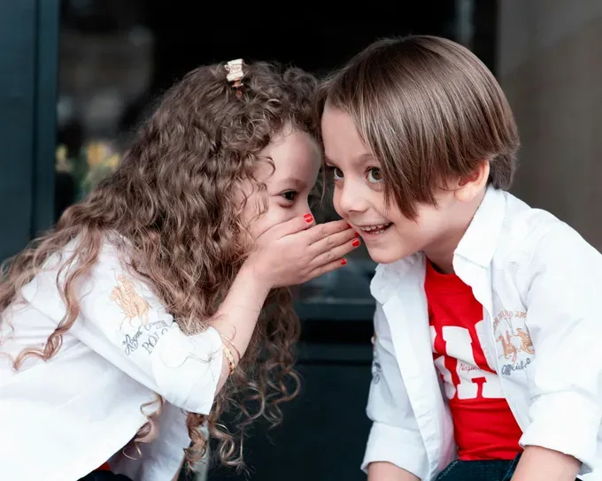 little girl whispering something to the little boy