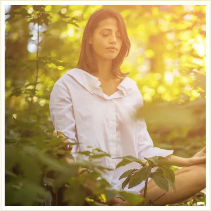 Woman outdoors in wilderness sitting in meditation