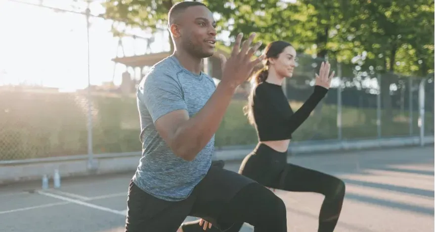 Man and woman working out outside in a park.