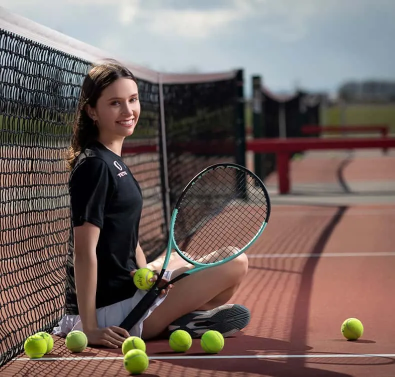 girl tennis player sitting on court with net behind her