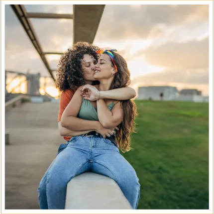 Couple sitting in a loving embrace with the sunrise behind them