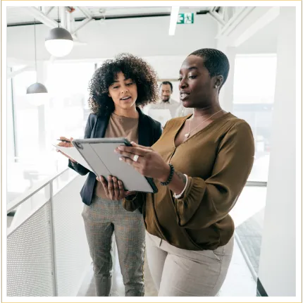 Two women in an office discussing a business plan on a tablet