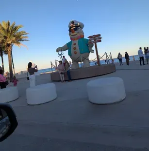 a daytime pic of the snowman taken from a distance with ppl posing in front of it