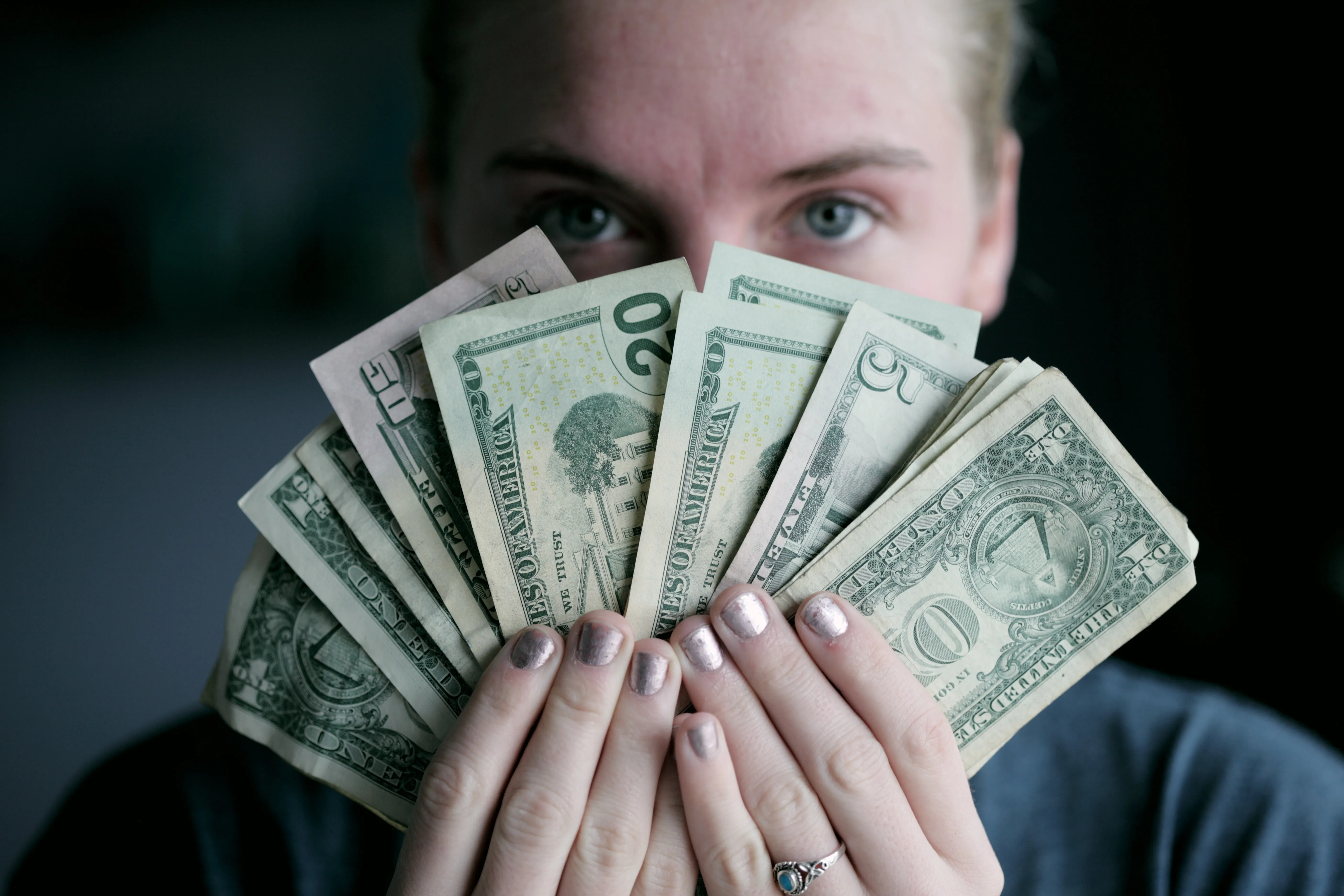 woman holding up a bundle of money in front of her face