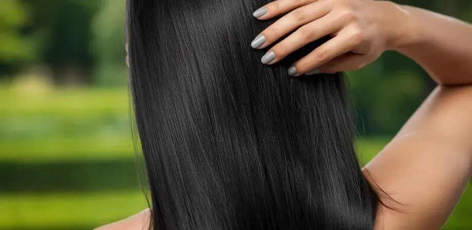 Una persona con cabello sano y fuerte, mostrando los resultados de la nutrición capilar interna con Spirulina y el cuidado externo con el Shampoo Ganozhi de DXN.