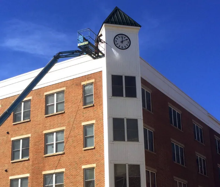 Power washing a large clock tower with a crane