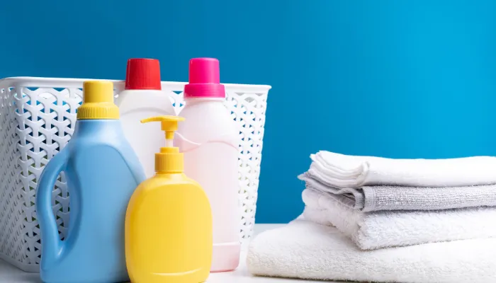 Bright colored pic of laundry detergent, laundry basket, and clean towels.