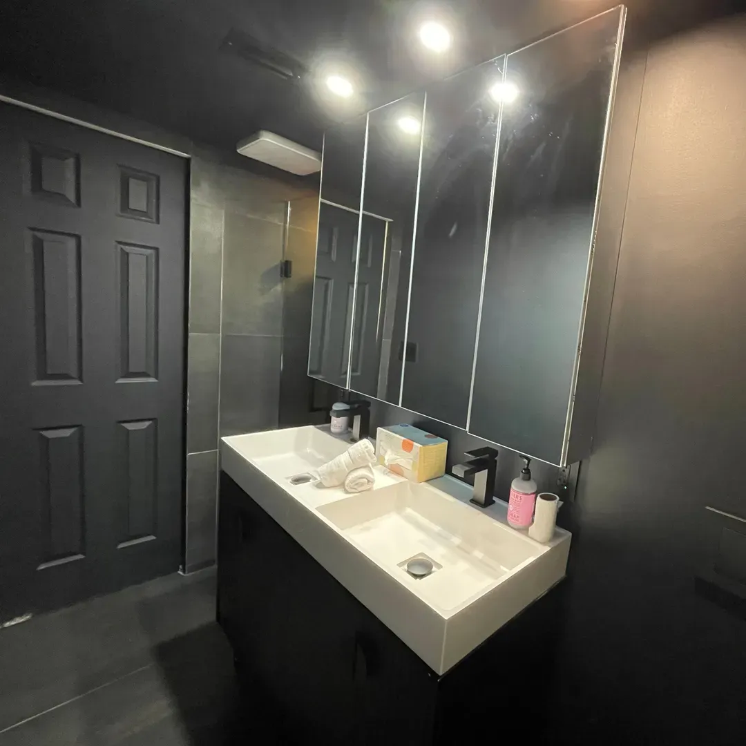 Bathroom Nr 2 with dimmer lights, a dual sink vanity, stand-alone shower, and double mirror wall cabinets.