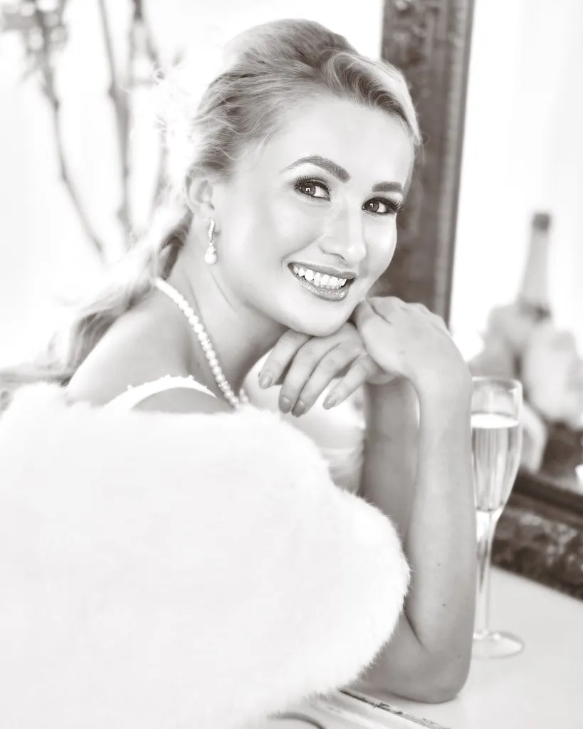 Black and white bridal portrait portrait of blonde woman wearing pearls smiling wearing a furry white shawl