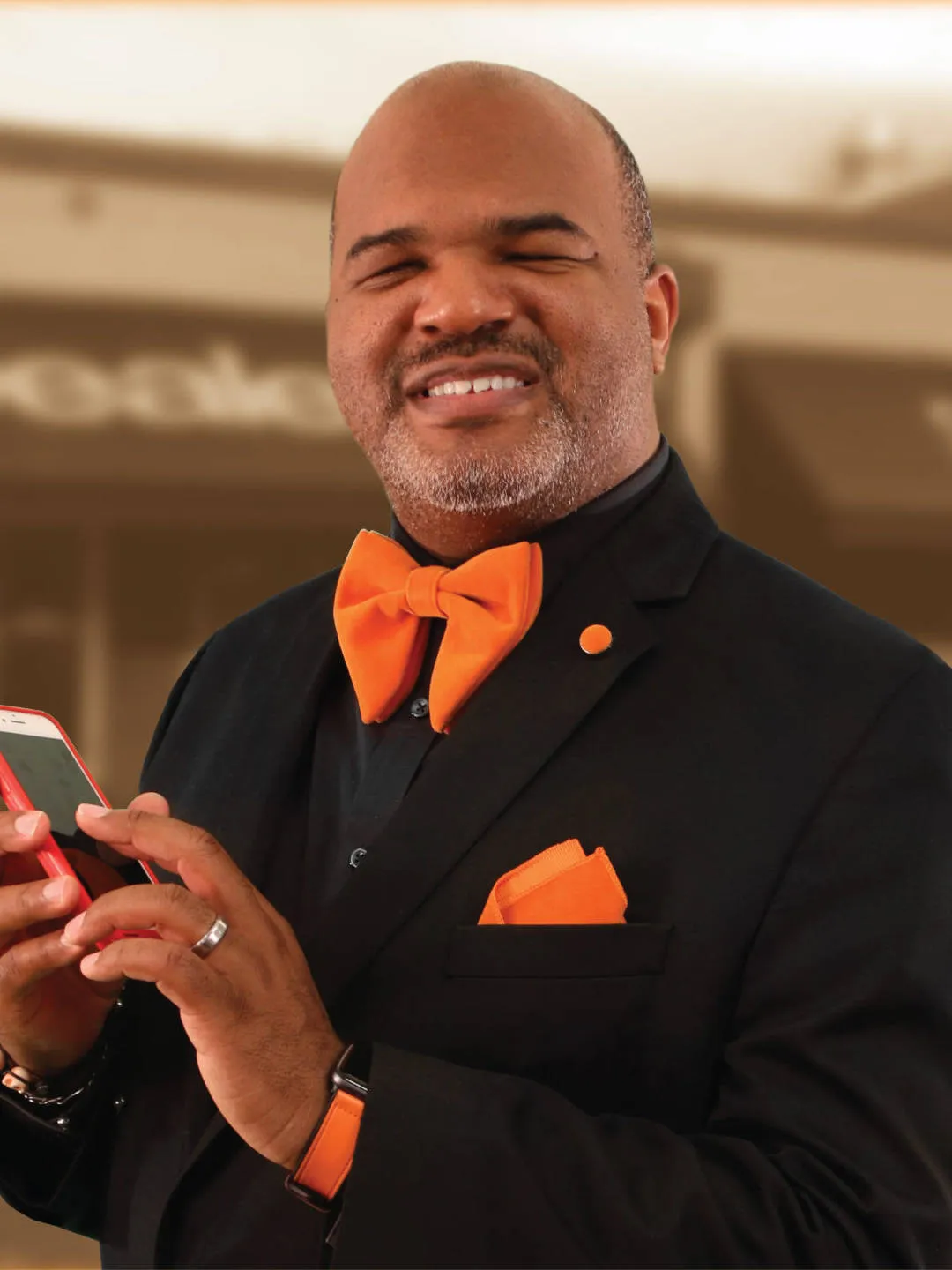 LA Williams an African American man wearing a black suit and orange bow tie