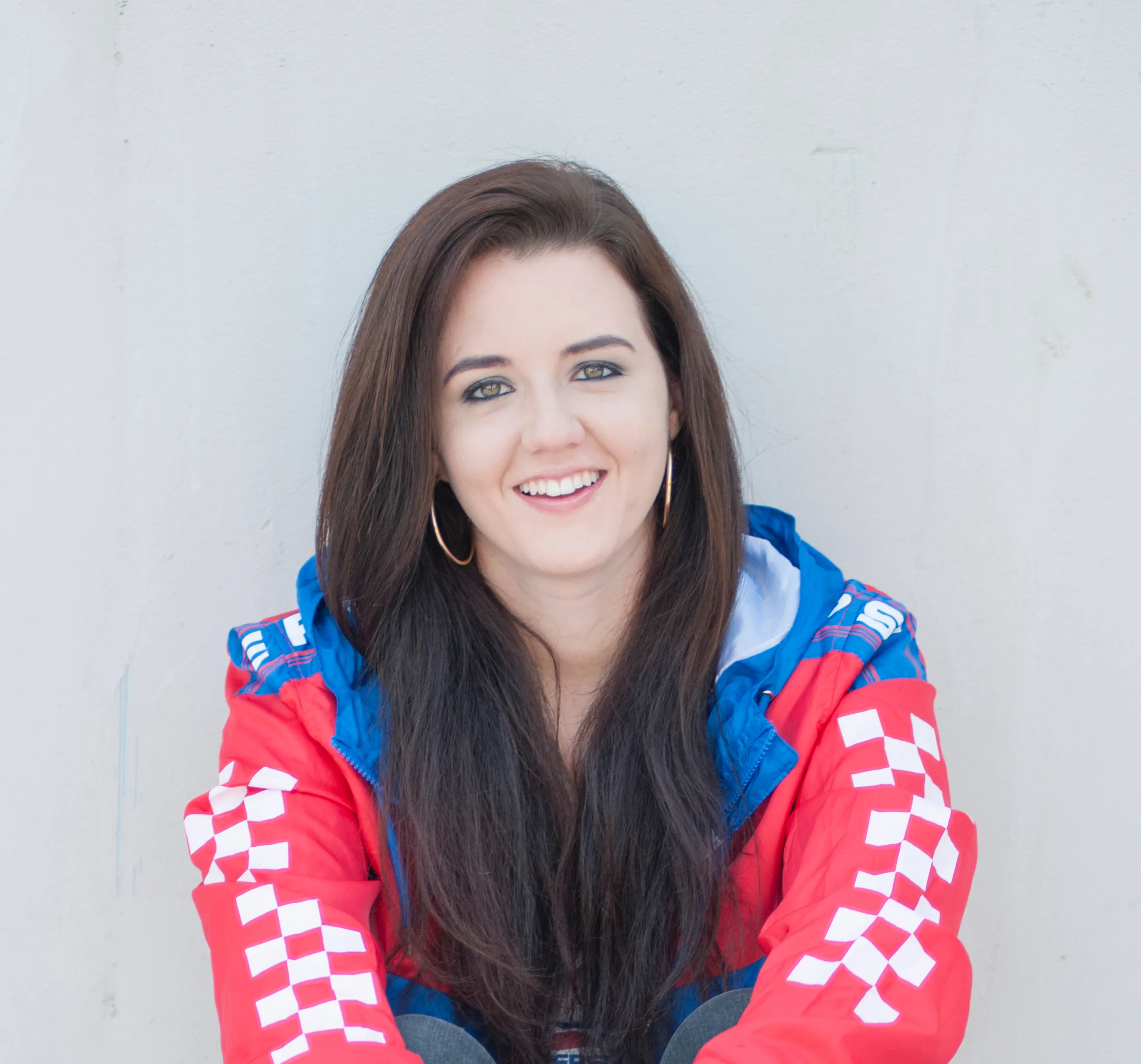 A headshot of a lady wearing a red, blue and white jacket