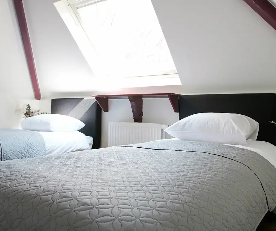 slaapkamer retraitelocatie met 2 bedden onder schuin dak met raam
