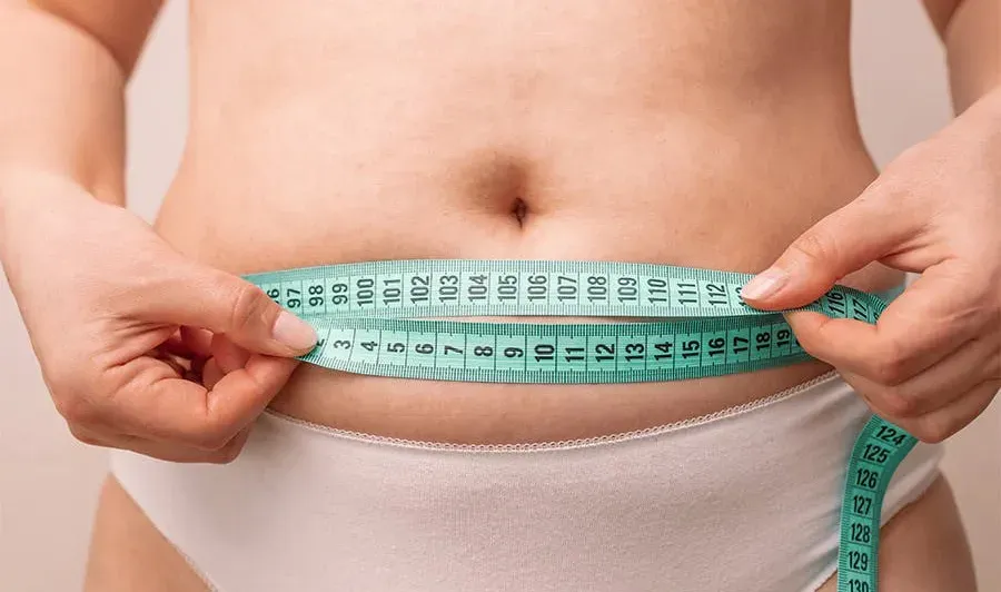 A woman in her underwear with measuring tape around her midsection.