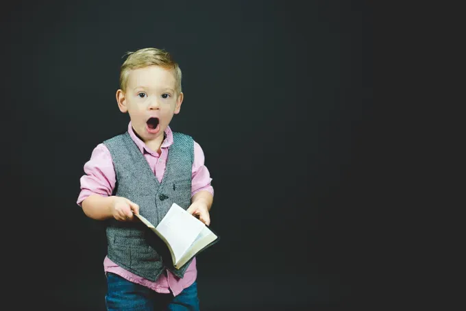 toddler looking at the camera while holding a book