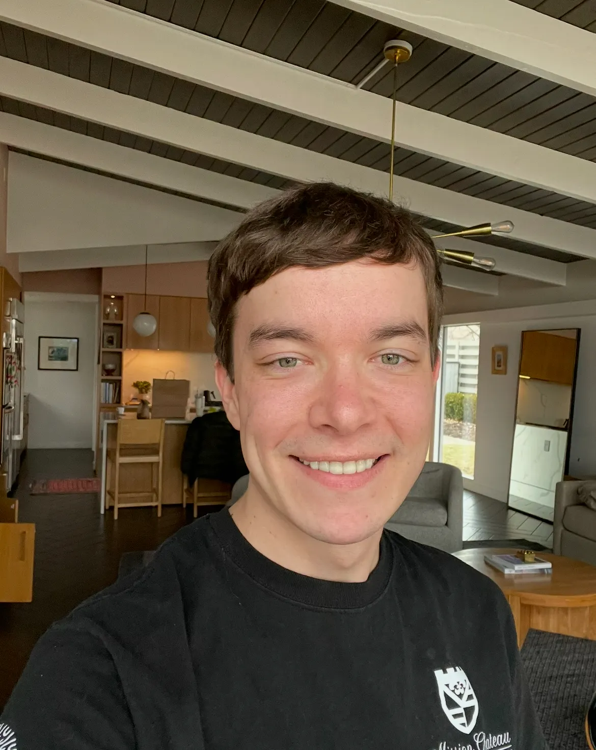 Kevin, a dog walker and pet sitter in Kansas City, smiles in a bright indoor living space with wood floors and modern decor behind him.